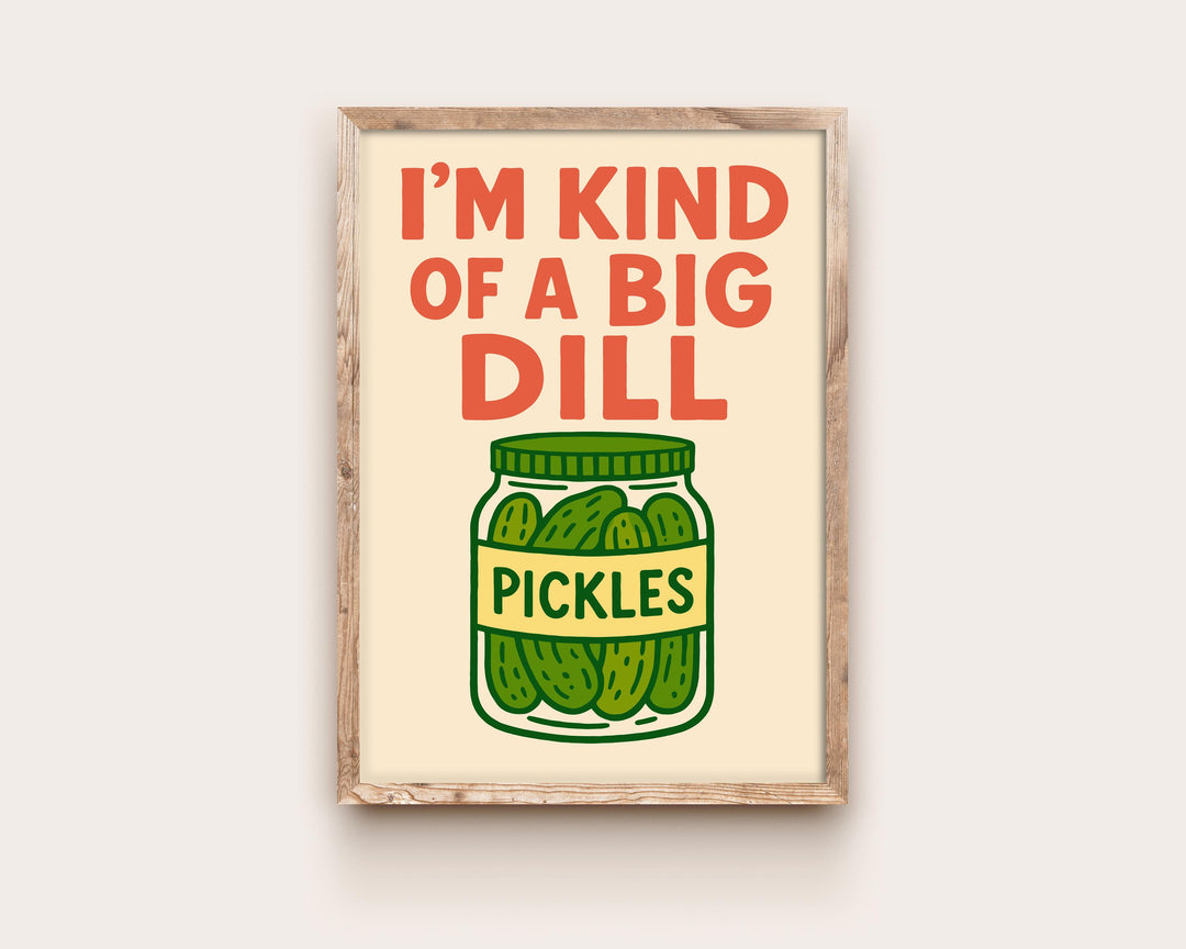 May include: A framed print featuring the phrase "I'M KIND OF A BIG DILL" in red, above a cartoon jar of pickles. The jar is green with a yellow label reading "PICKLES". The background is a light beige colour.